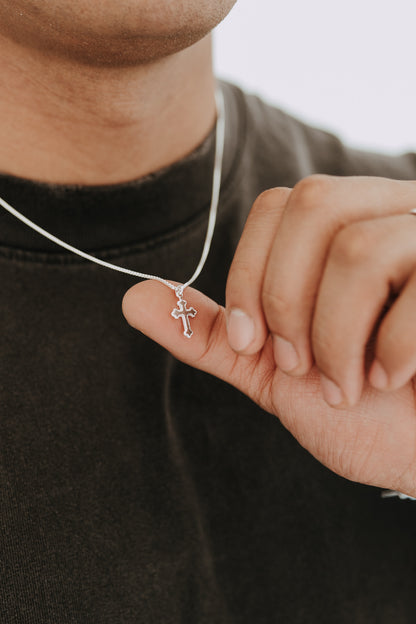 Close-up of silver cross pendant necklace styled with black streetwear