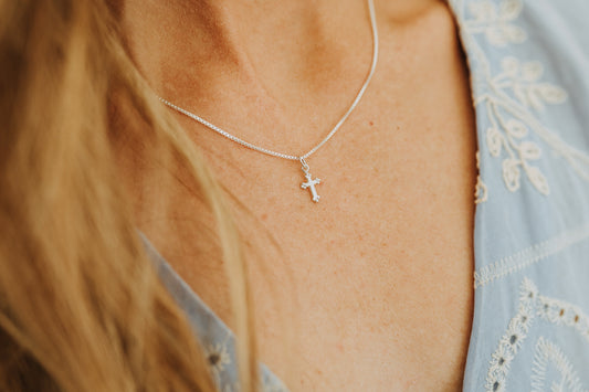Woman wearing minimal sterling silver cross necklace
