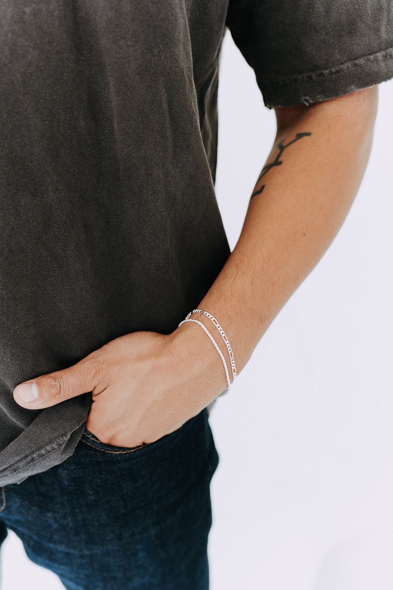 Polished sterling silver Figaro bracelet on tattooed male wrist