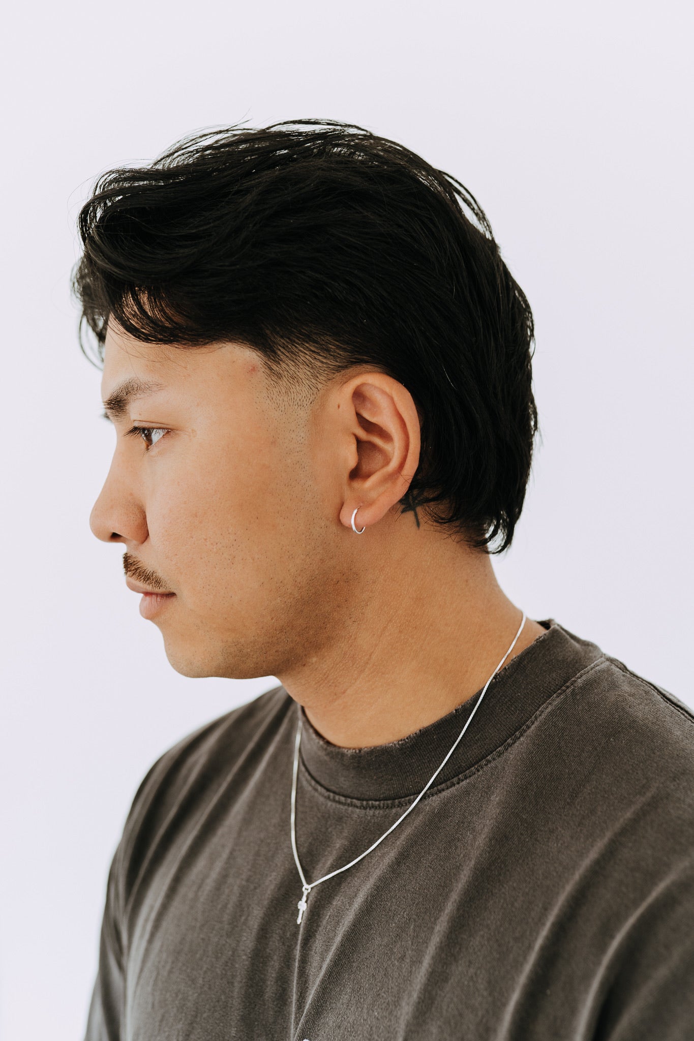 Minimal sterling silver hoop earring worn by a man with a classic casual style.