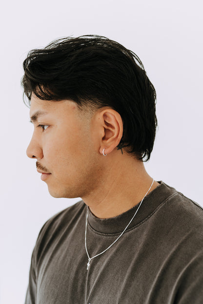 Minimal sterling silver hoop earring worn by a man with a classic casual style.