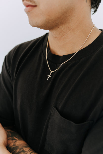 Minimal gold cross necklace for men featuring a detailed engraved pendant and rope chain