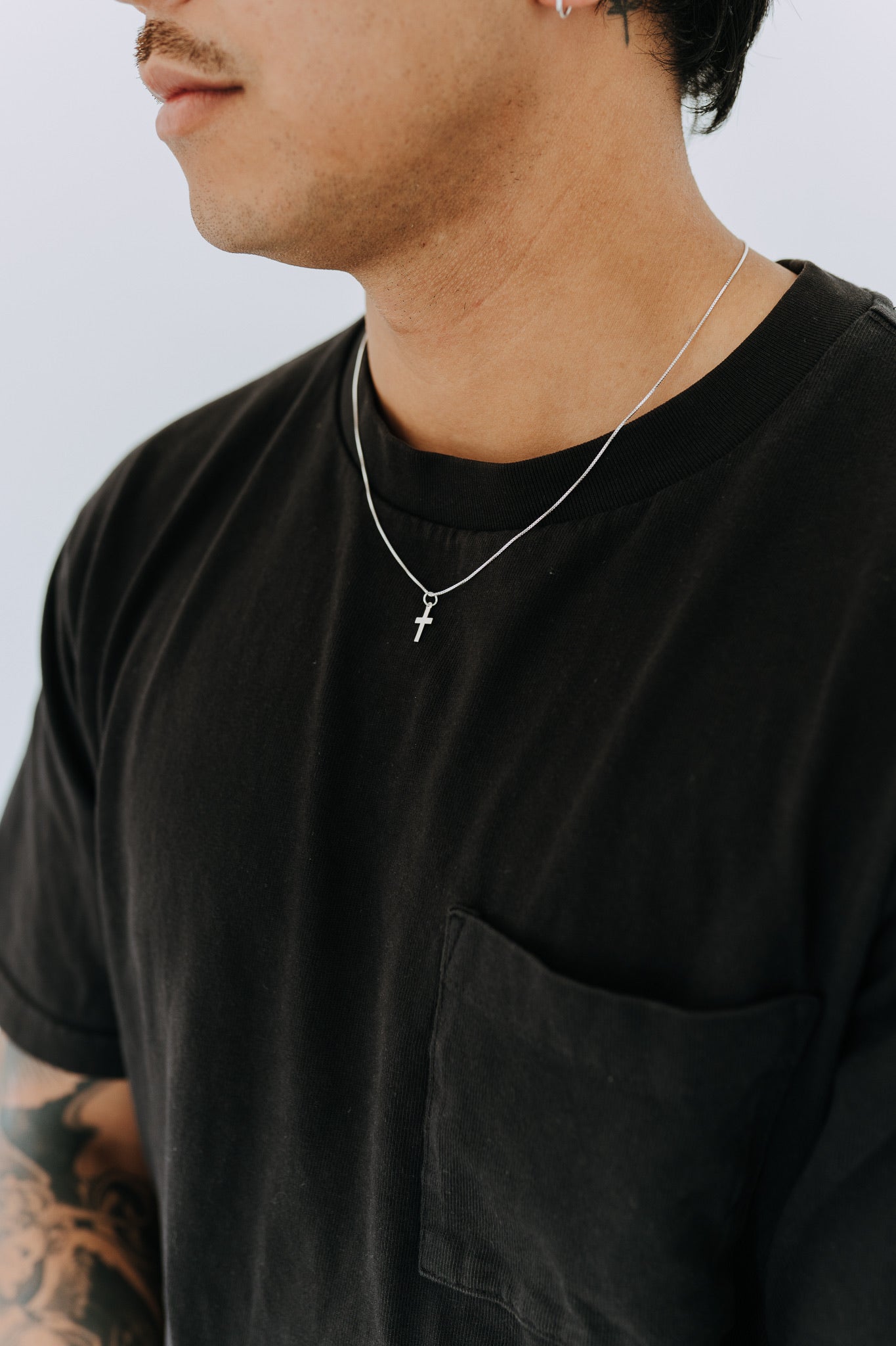 Simple sterling silver cross pendant necklace styled with black tee