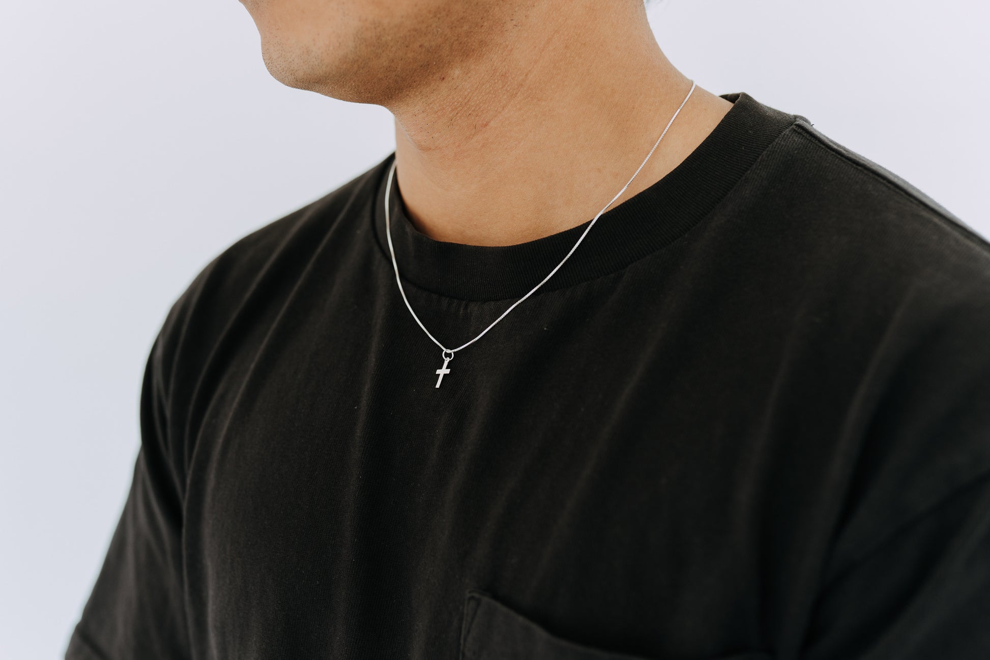 Men’s silver cross pendant necklace worn casually with black shirt