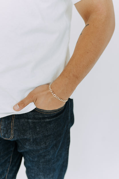 Men’s gold curb chain bracelet styled with white tee and dark denim for an everyday look