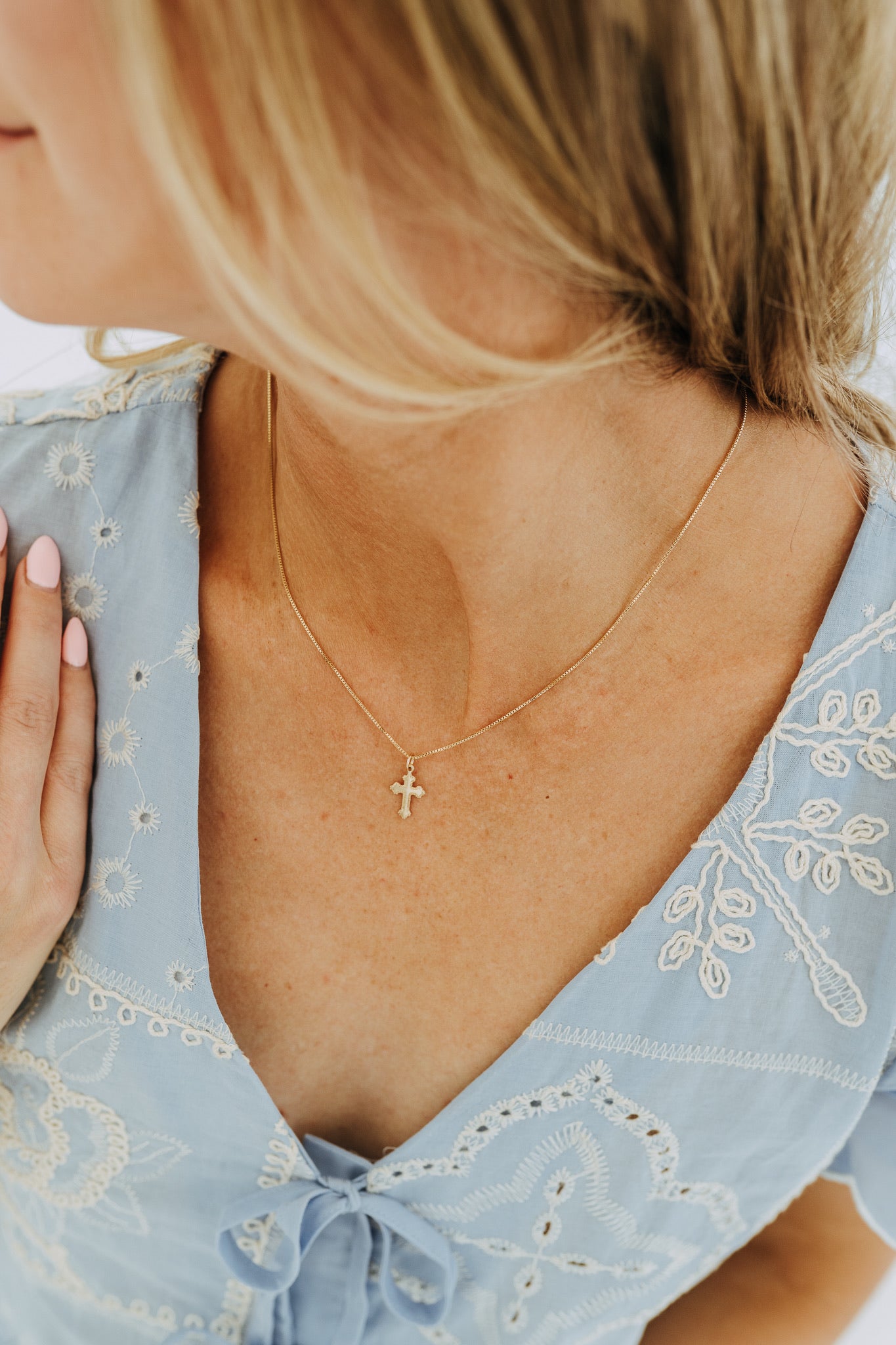 Close-up of detailed gold cross necklace on model