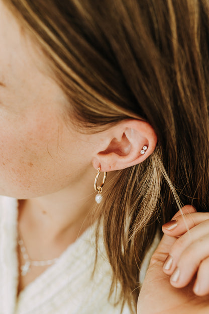 Minimal pearl hoop earrings modeled on ear with stacked piercing styling